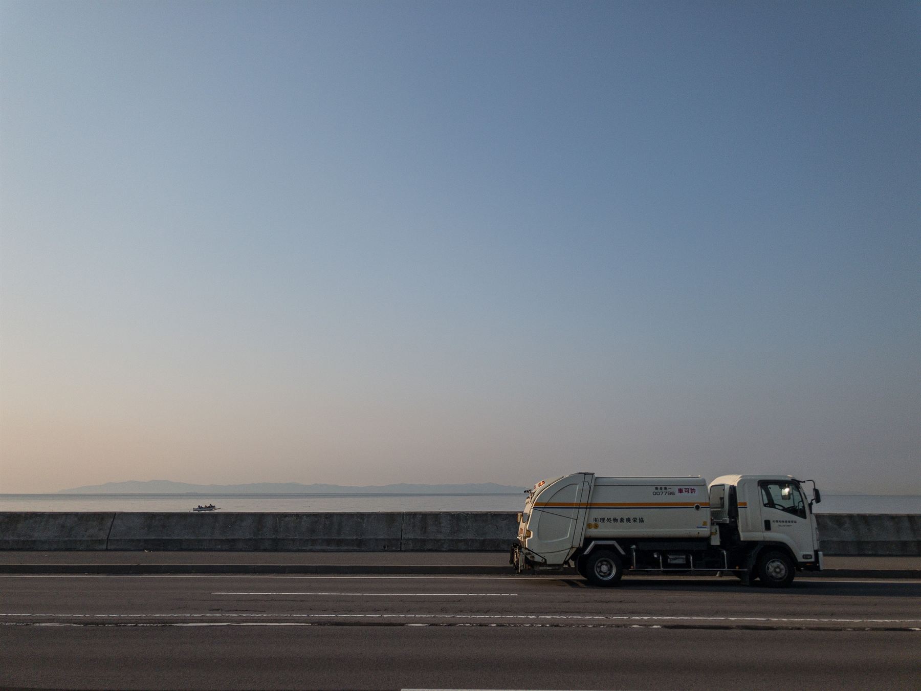 海沿いを走る産業廃棄物収集運搬車
